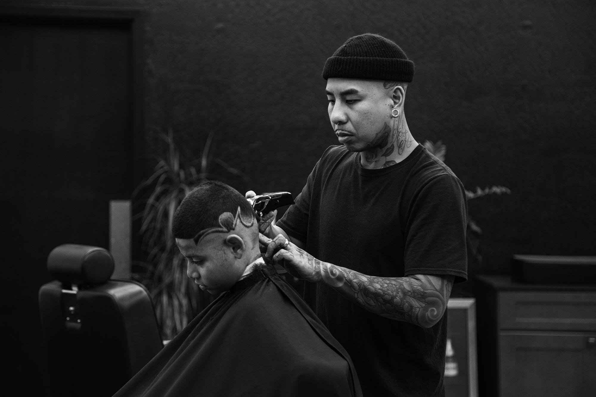A barber giving a client a haircut and fade at Rich in Flesh Tattoo & Barber shop in Livermore, CA