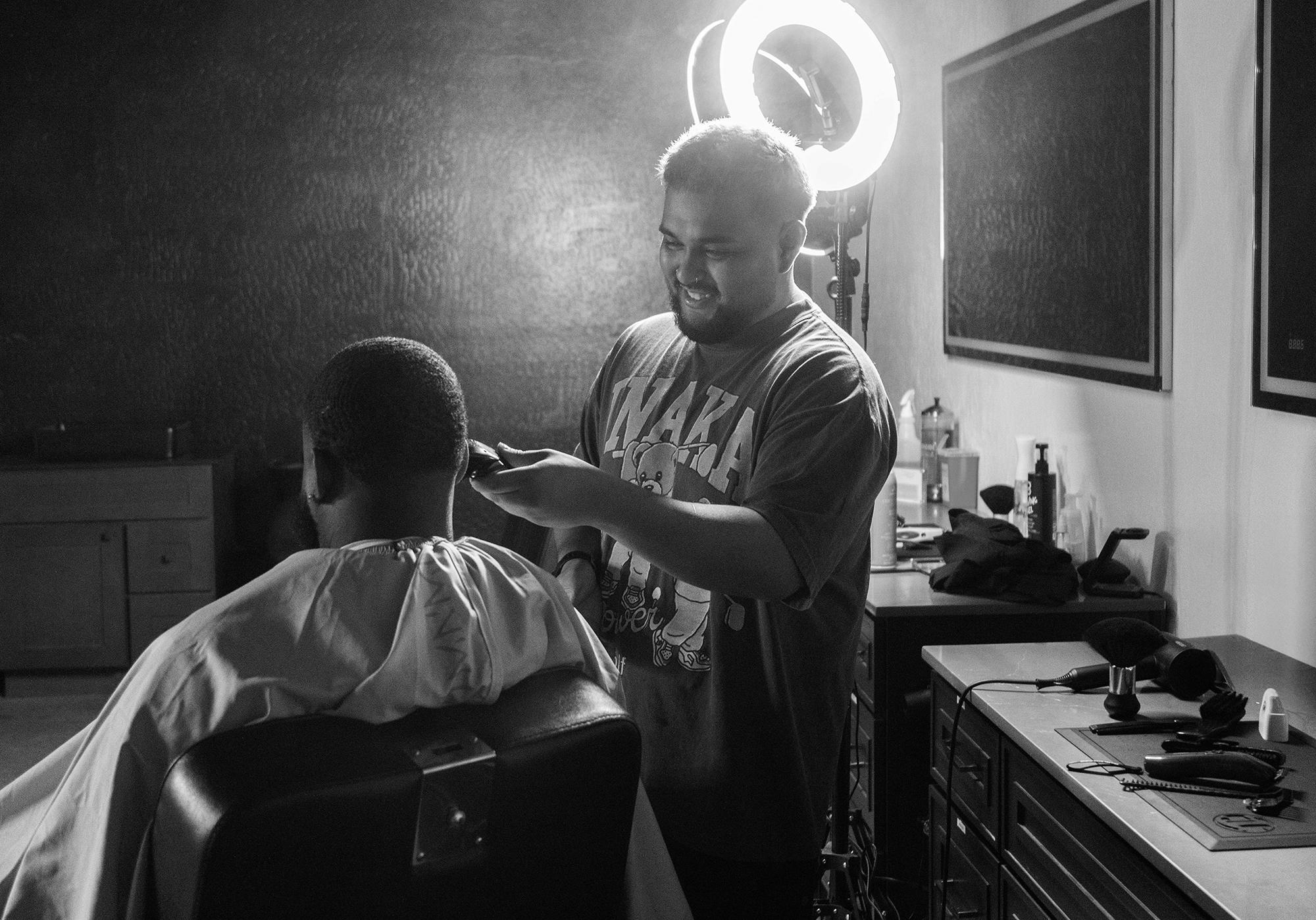 A barber with clippers giving his client a fade haircut at Rich in Flesh in Livermore, CA